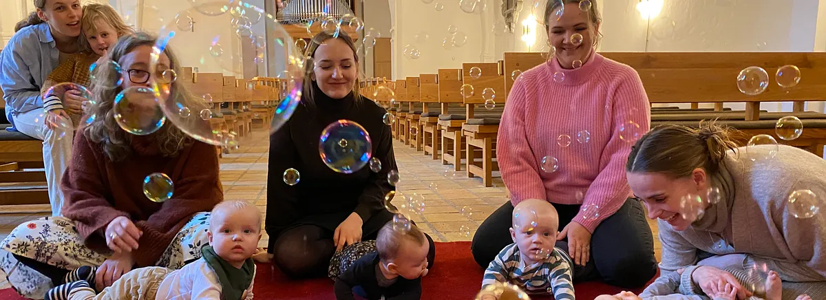 Præsten blæser sæbebobler ud over babyer til babysalmesang