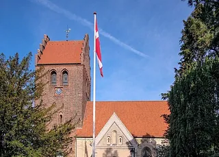 Hejst flag foran kirke